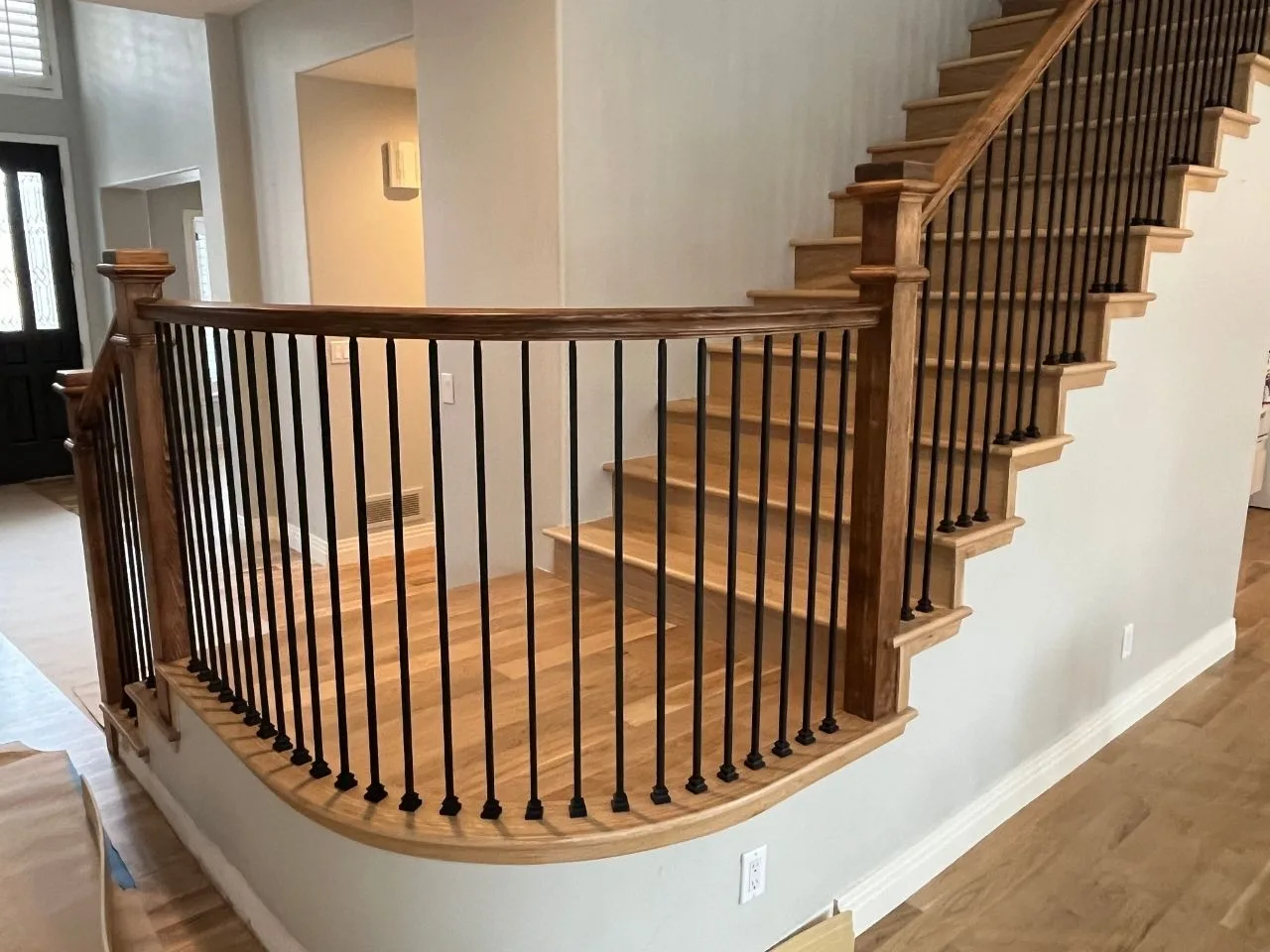 Curved staircase with iron balusters and wood treads