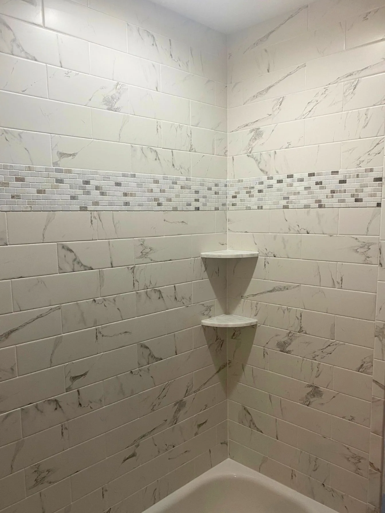 Marble subway tile shower with built-in corner shelves