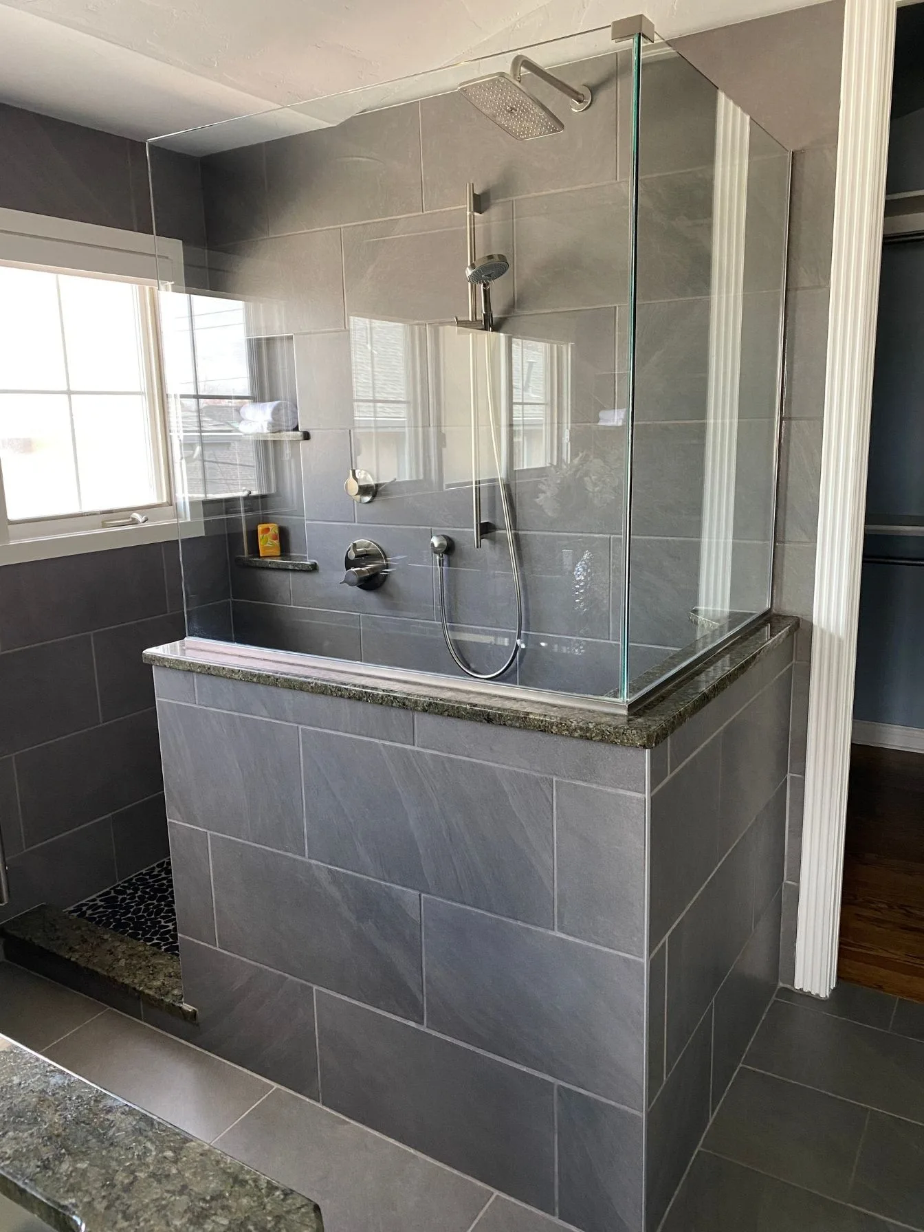 Tiled shower with a glass enclosure in a remodeled bathroom