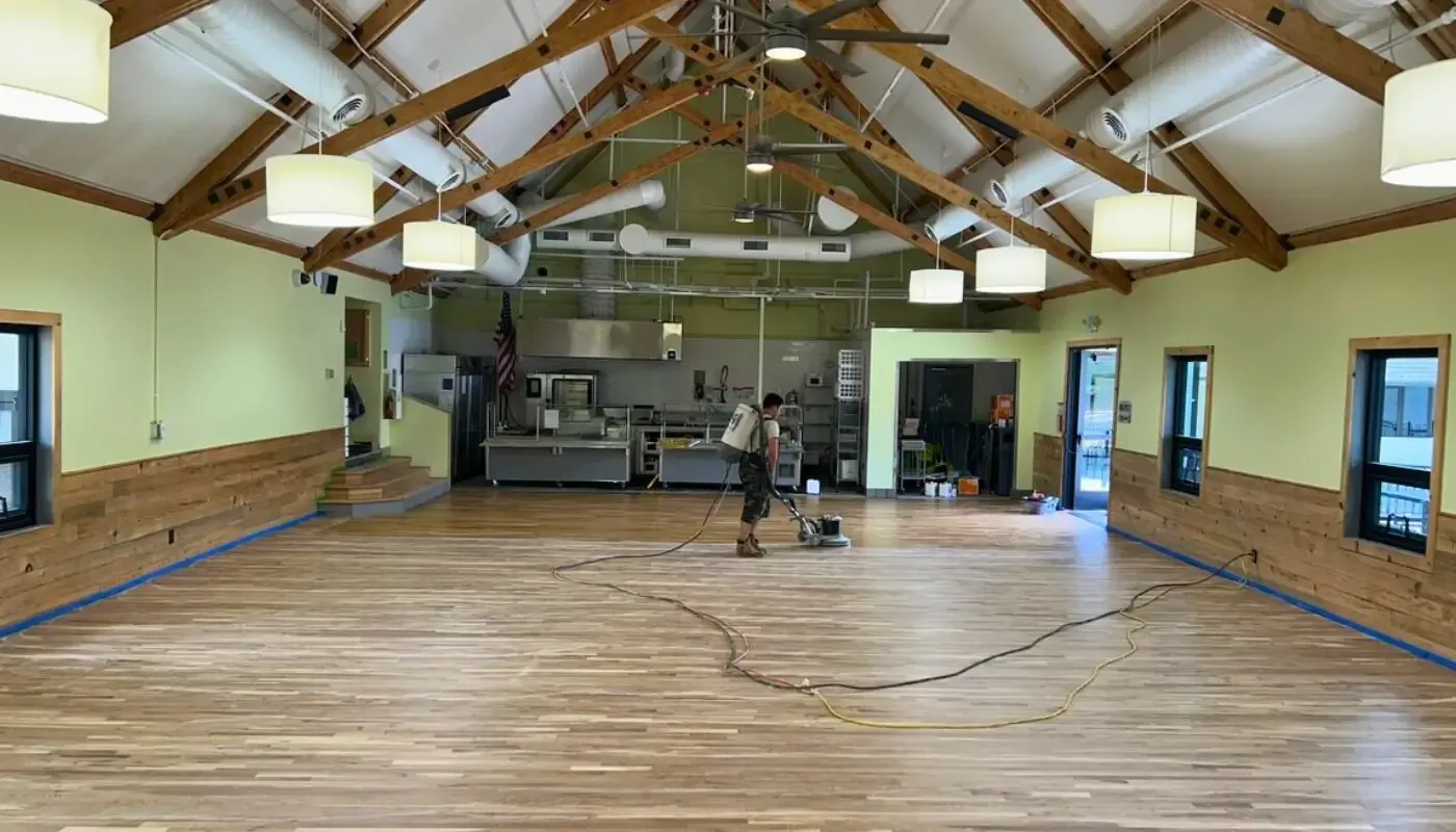 Crew refinishing the wood floor of a vaulted community hall