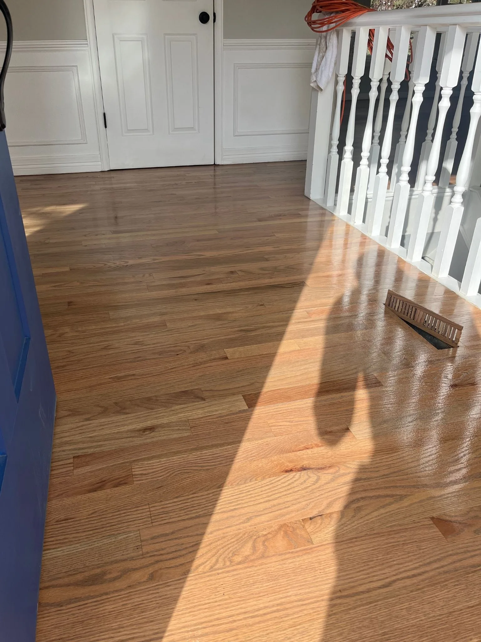 Hardwood floor running through a hallway and up to a painted staircase
