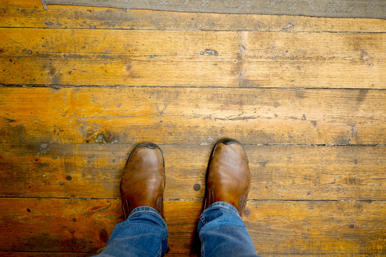Standing on a worn hardwood floor during a repair assessment
