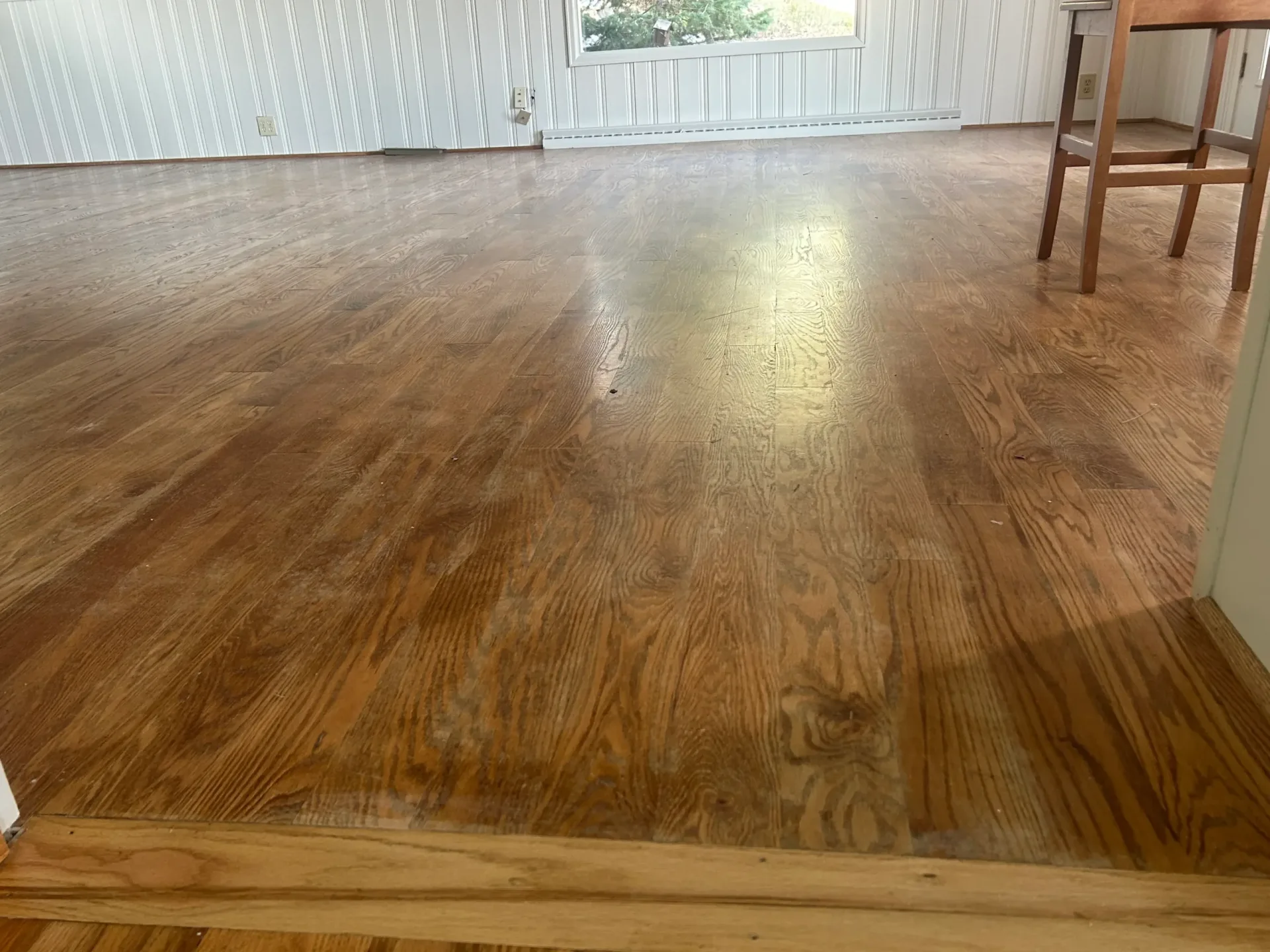 Light oak floor refinished in a room with beadboard walls