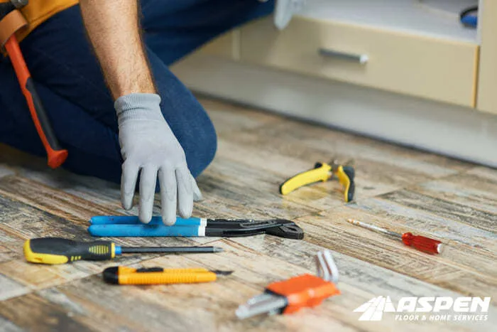Hand tools laid out on a floor during a hardwood repair
