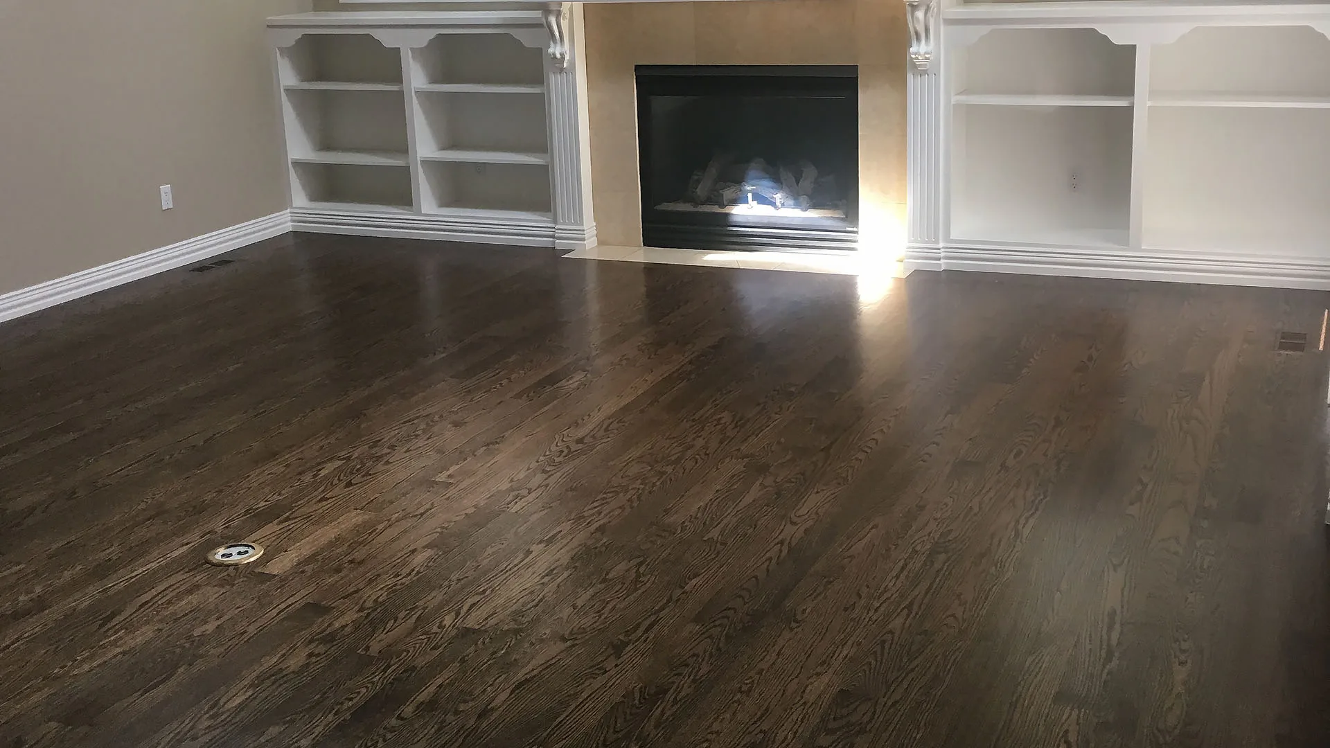 Dark wood floor in a room with white built-ins and a fireplace
