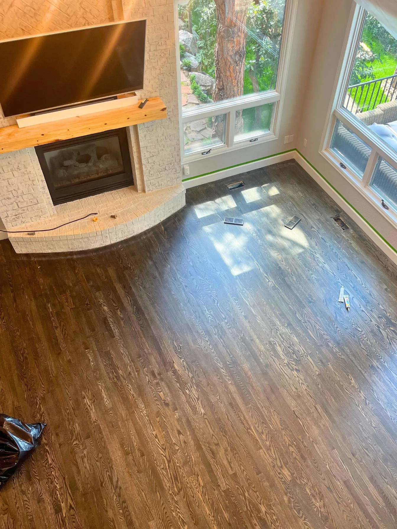Glossy refinished floor beside a stone fireplace