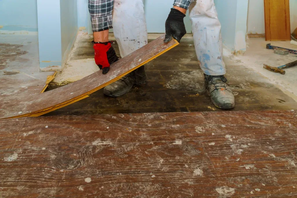 Technician working to fix hardwood floor damage by replacing a damaged board in a Denver home