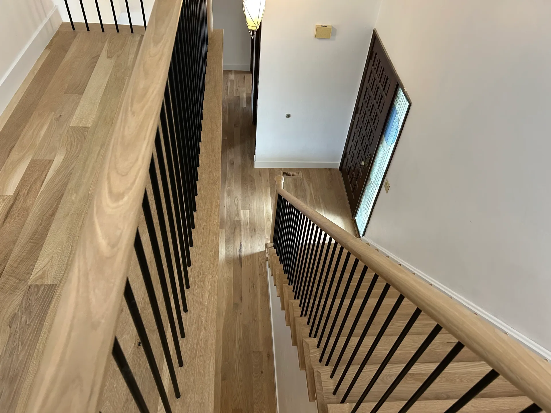 Open stairwell with iron balusters and a wood handrail
