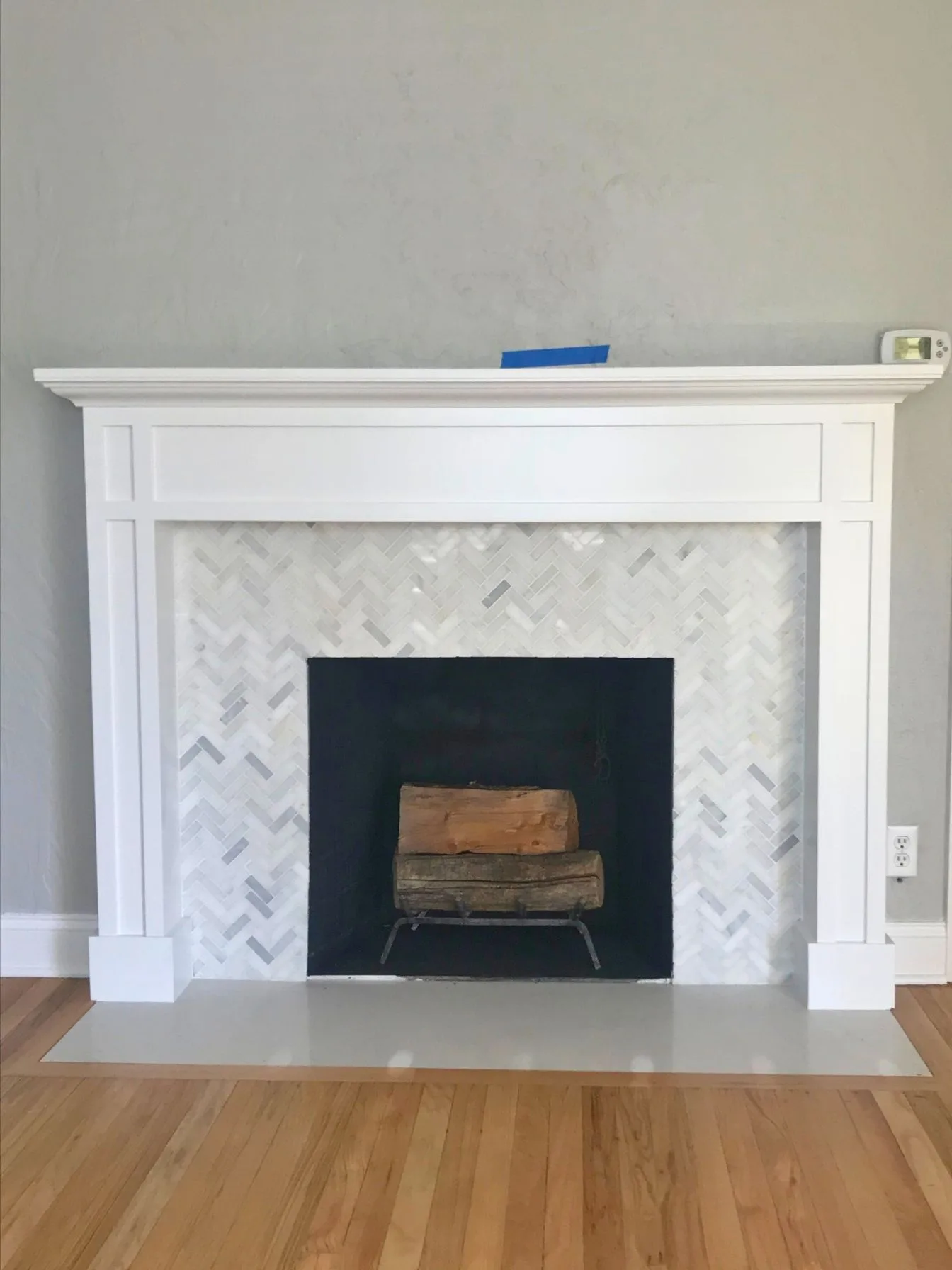 White fireplace surround with herringbone marble tile