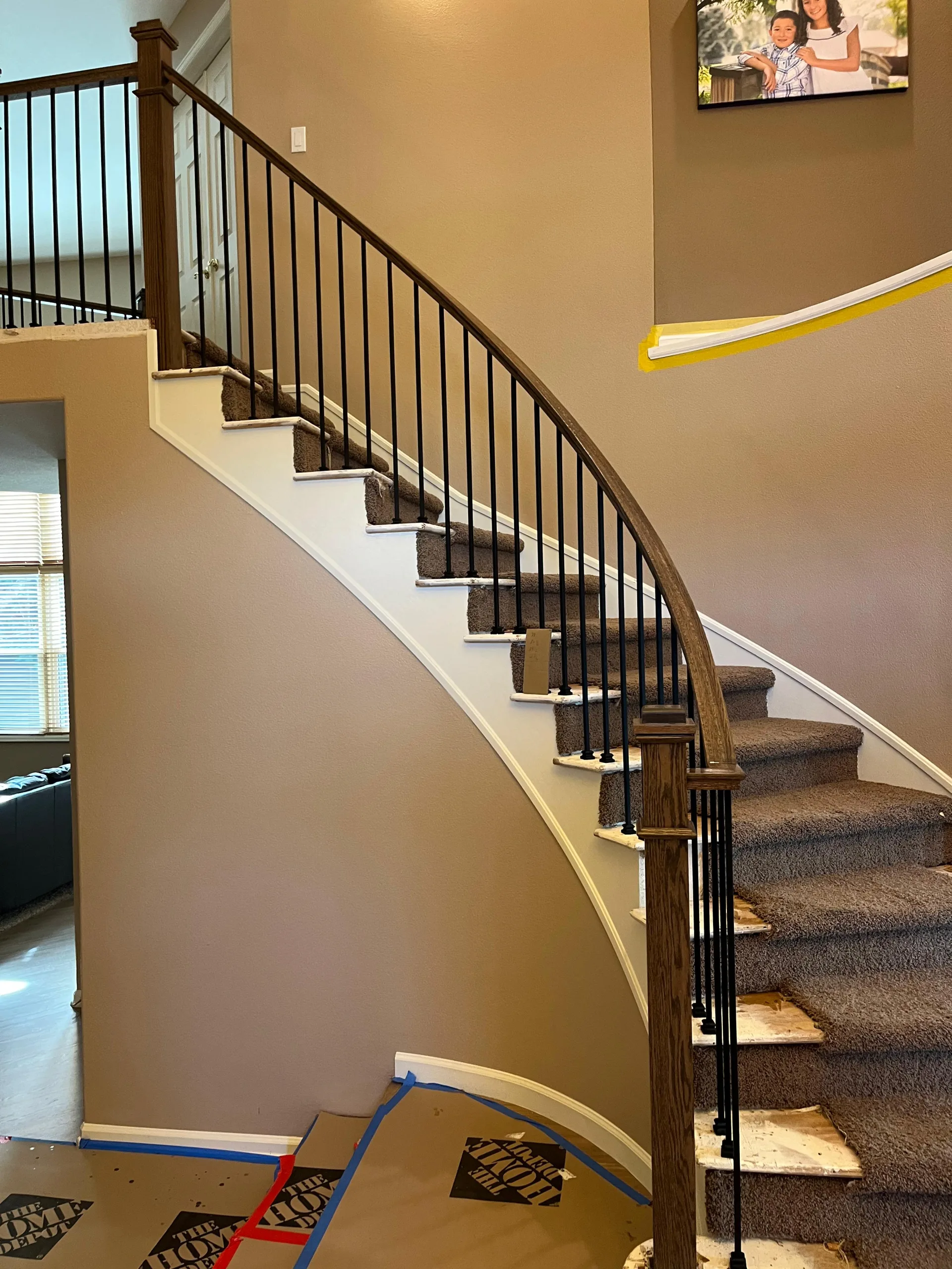 Curved staircase with iron balusters and a wood handrail