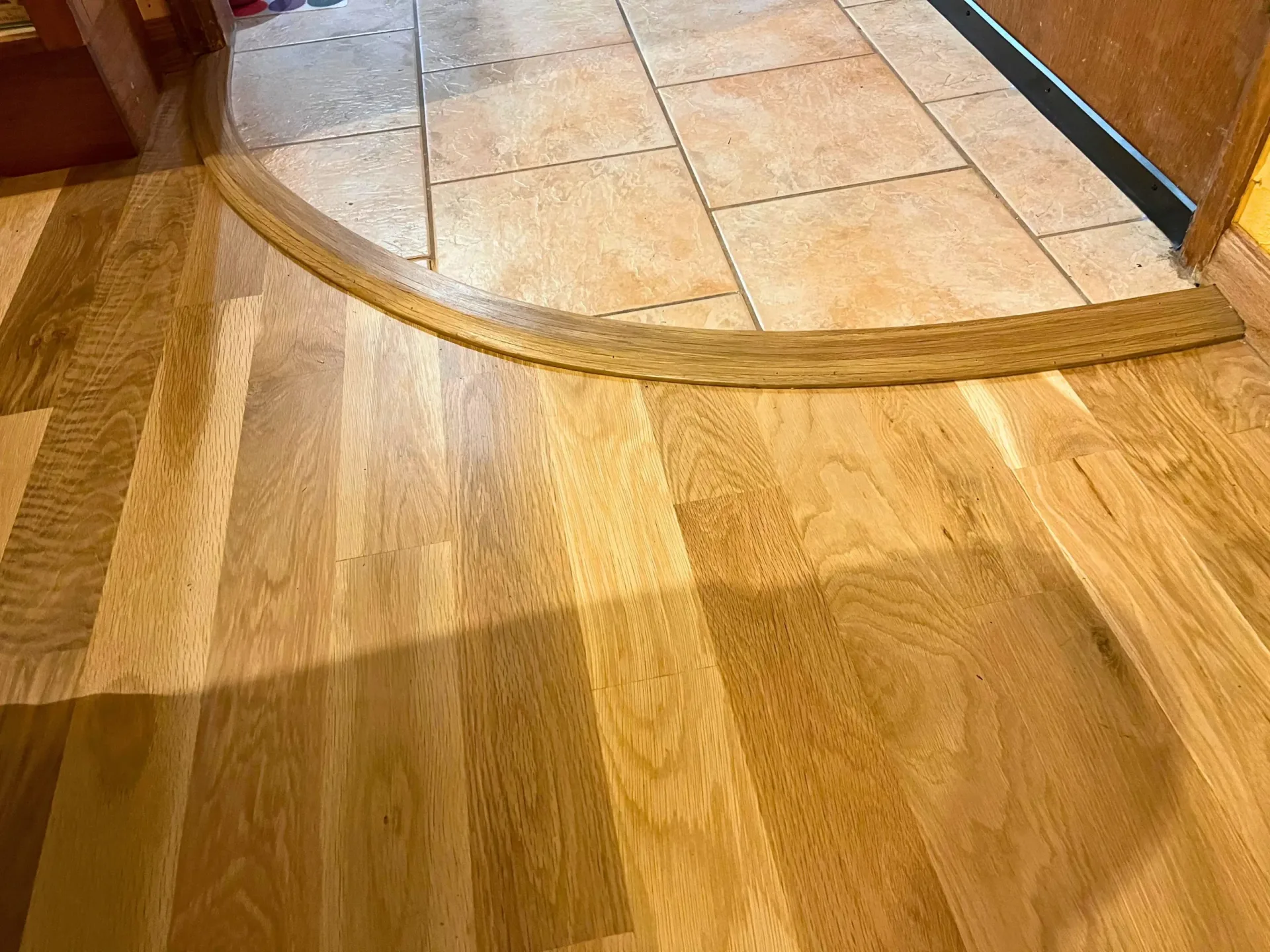 Curved transition where a wood floor meets tile
