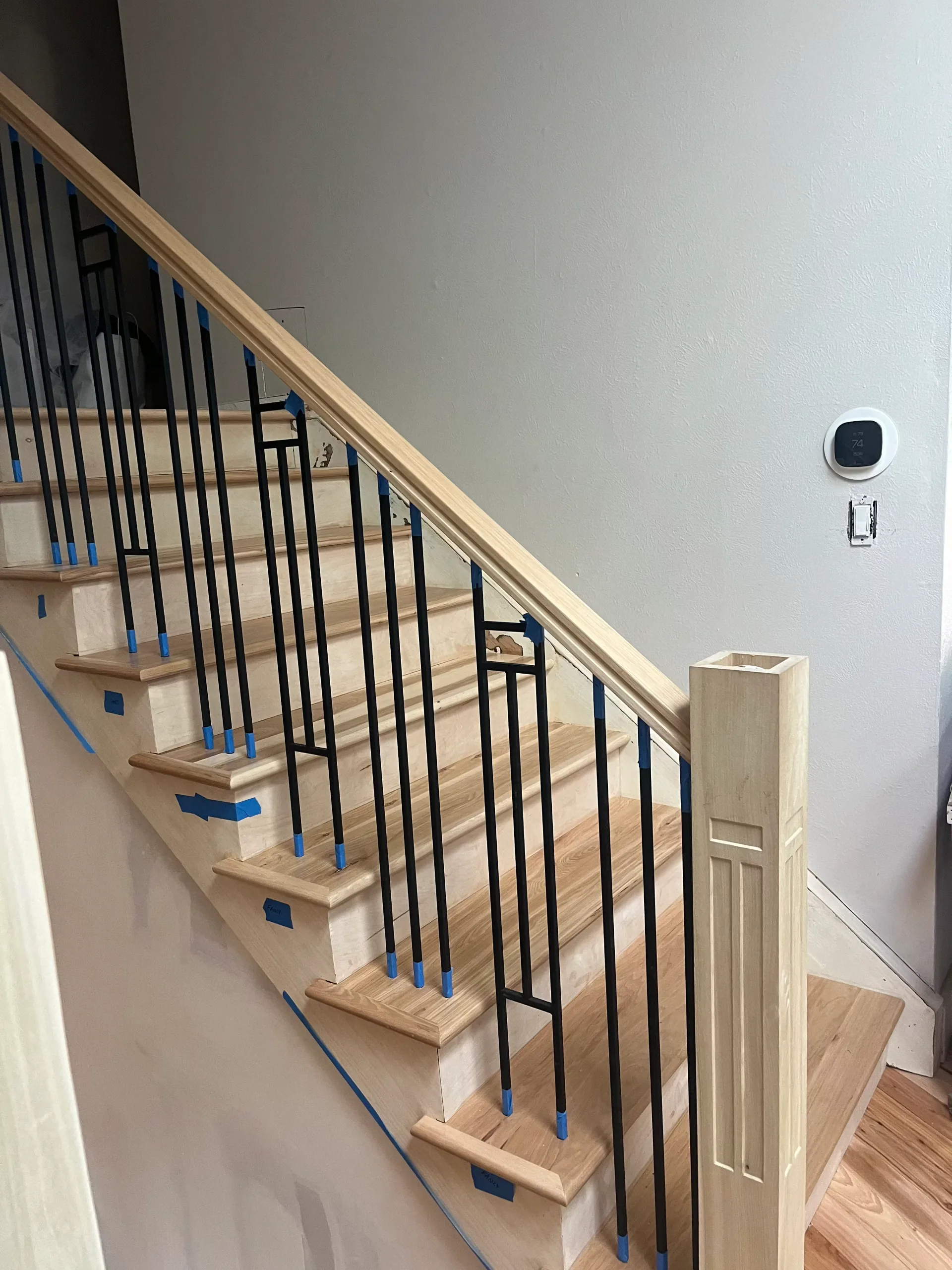 Staircase with iron balusters, taped off during installation