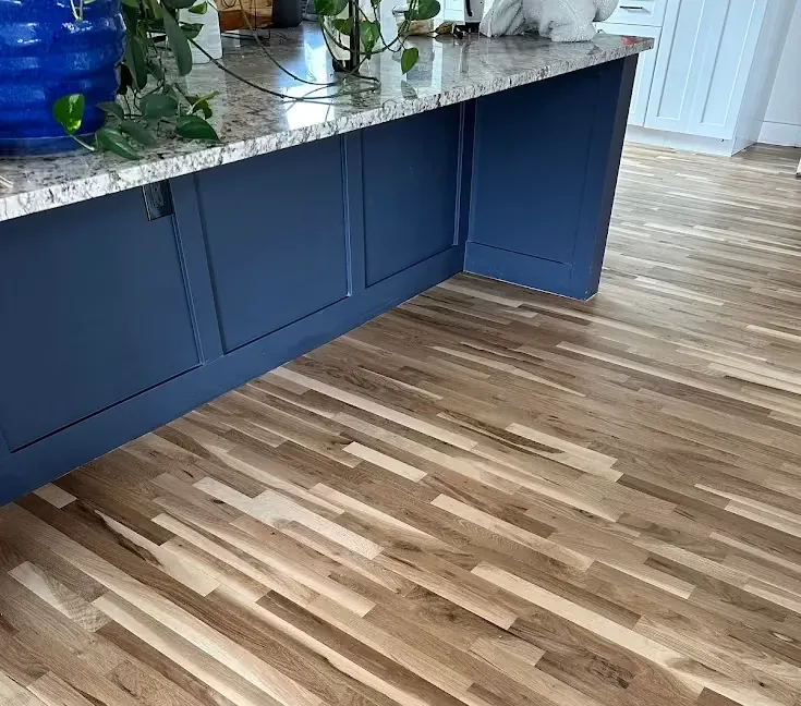 Refinished light oak floor beside a navy kitchen island with a granite top