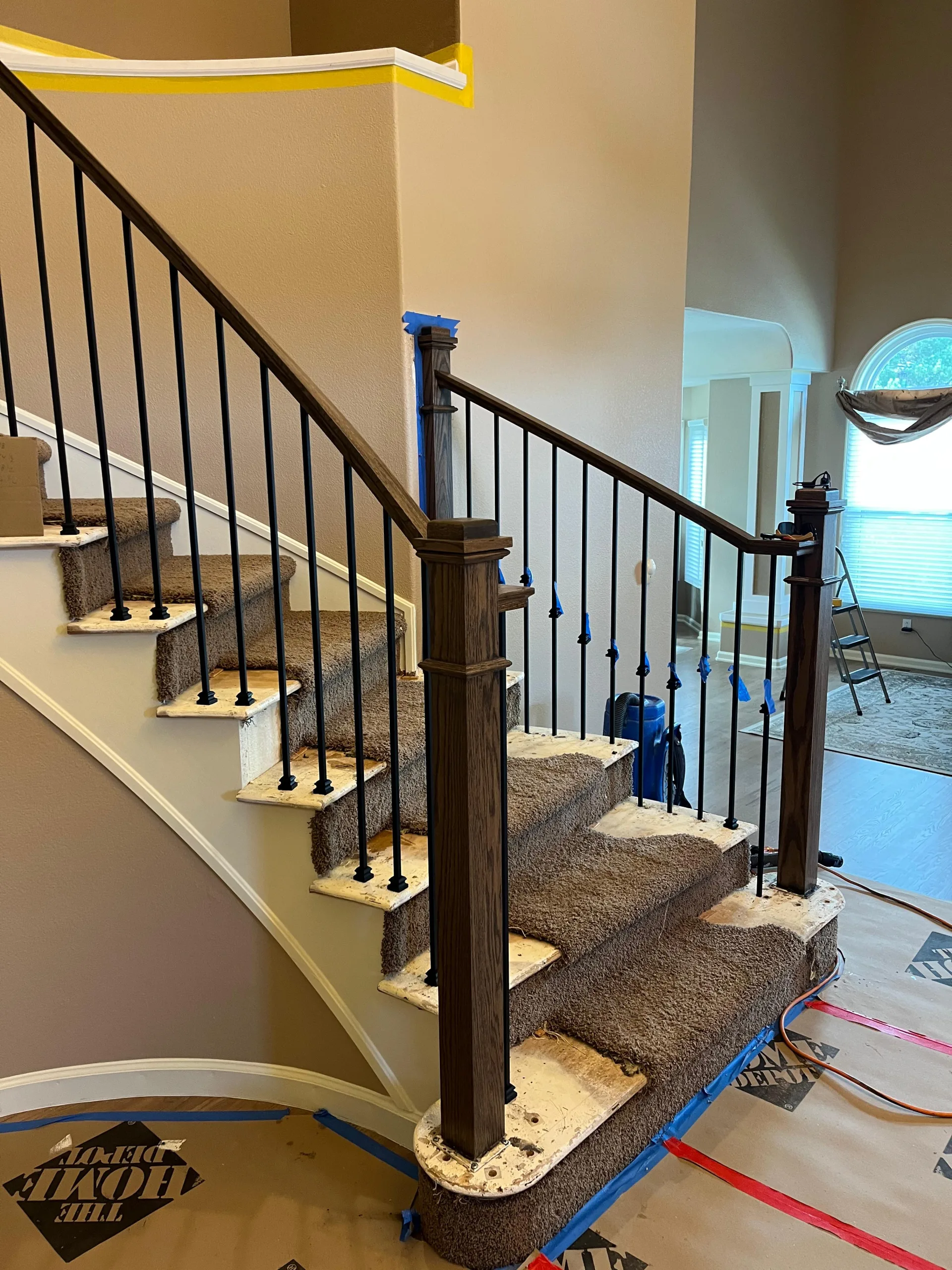 Close view of a dark newel post and iron balusters on a curved staircase