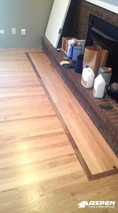 New boards laid beside a brick hearth during a floor repair