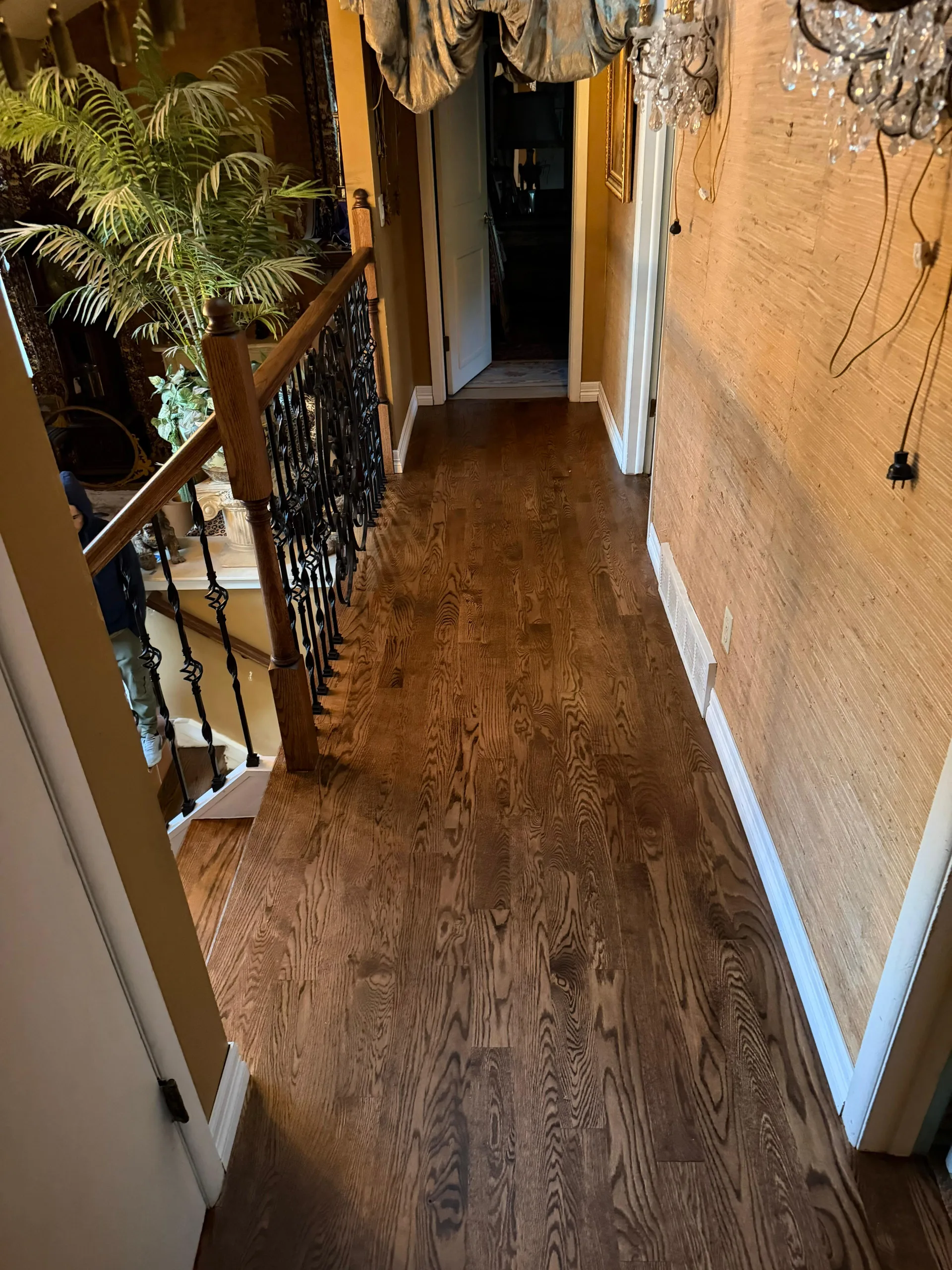 Dark wood floor running down a hallway beside an iron railing