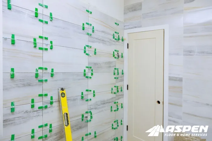 Wall tile going up with levelling clips and a spirit level