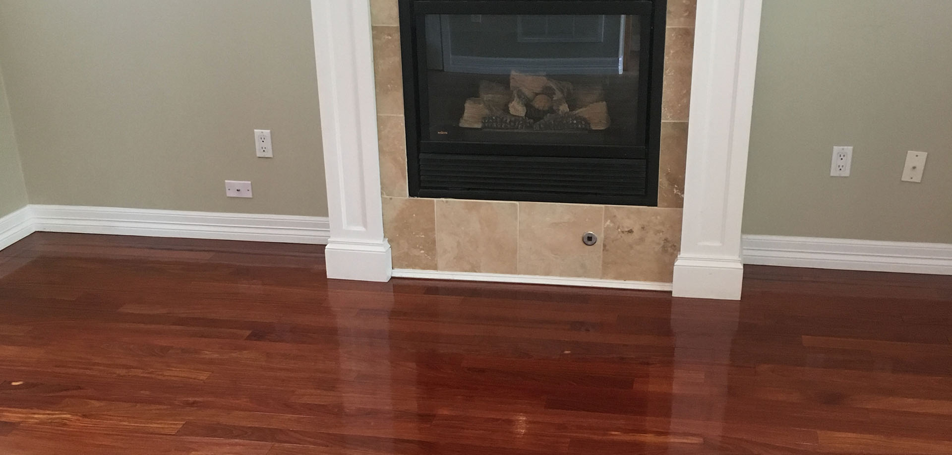 Hardwood flooring with a glossy finish in a cozy living room setting featuring a fireplace and neutral wall color, illustrating ideal flooring for Denver homes.