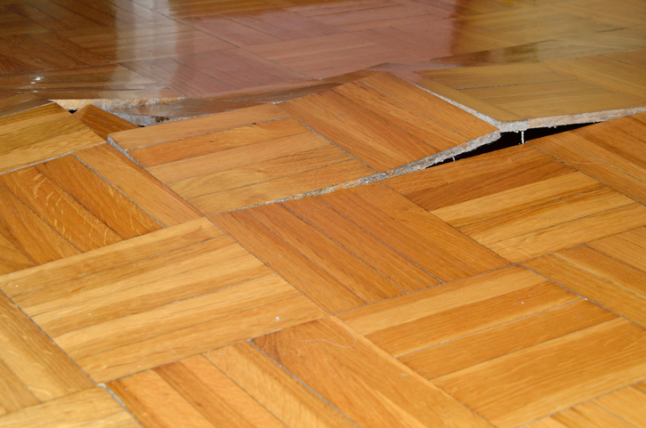 Poorly installed hardwood floor with visible gaps and uneven planks