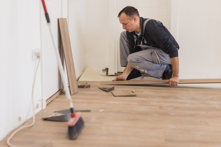 Worker carefully installing engineered hardwood flooring in a home