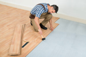 Worker performing wood flooring installation services in a home