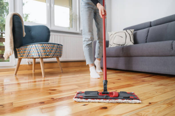 Homeowner cleaning and maintaining engineered hardwood floors in a living room