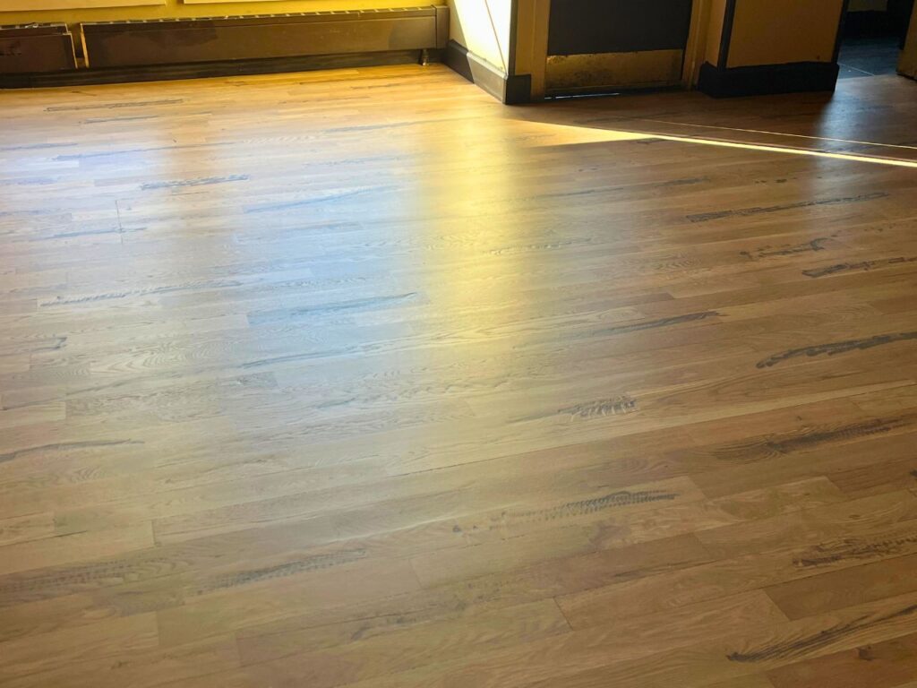 Expert craftsman installing 5-inch wide engineered maple hardwood planks in luxury Cherry Creek