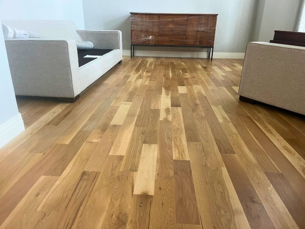 Refinishing crew sanding and applying natural finish to maple hardwood floors in Ken Caryl ranch home showing light wood grain