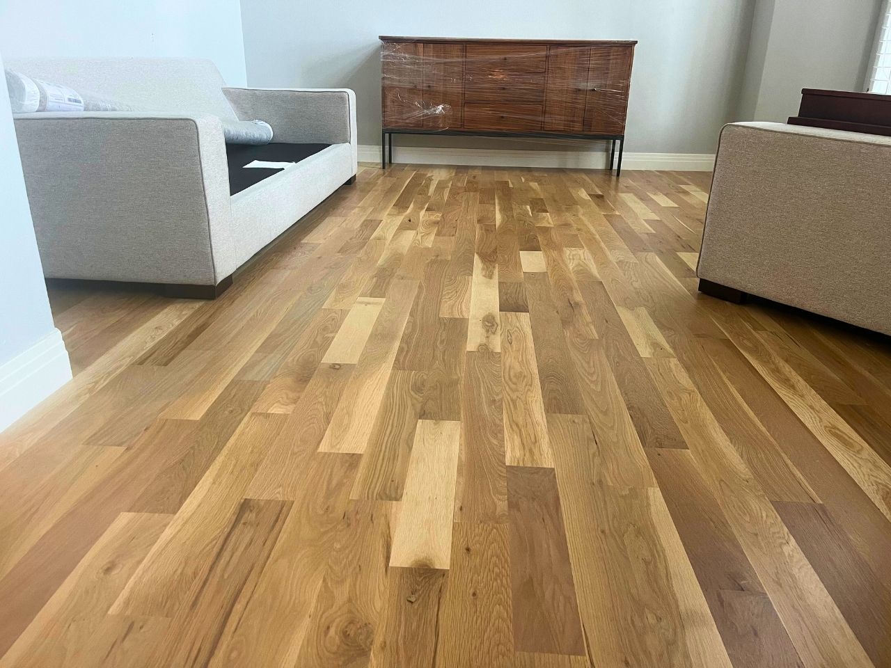 Refinishing crew sanding and applying natural finish to maple hardwood floors in Ken Caryl ranch home showing light wood grain
