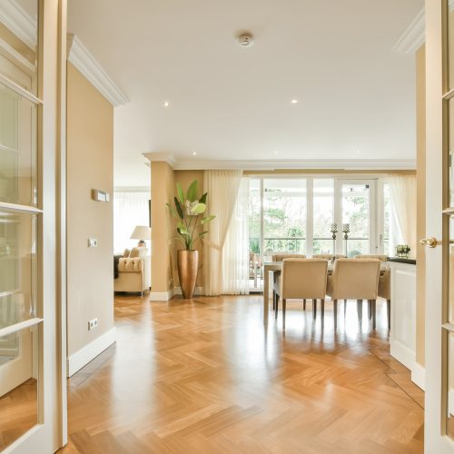 a living room with wood flooring and glass doors leading to the dining area in the room is very clean