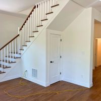 Professional installing exotic acacia engineered hardwood with golden color variations in new construction Thornton home