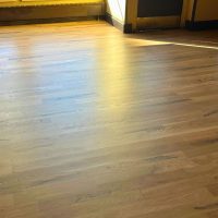 Expert craftsman installing 5-inch wide engineered maple hardwood planks in luxury Cherry Creek