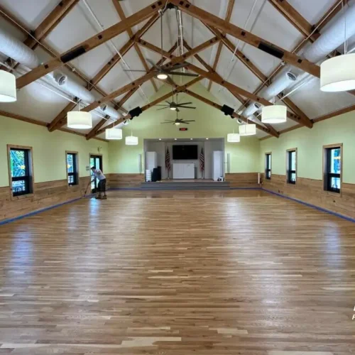 Professional applying dustless hardwood floor refinishing in Denver commercial space